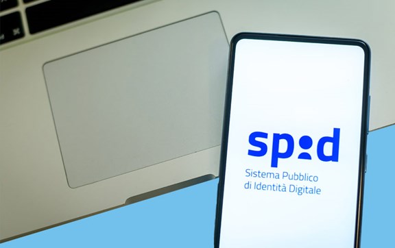 Porzione di portatile con sopra uno smartphone collegato allo spid.