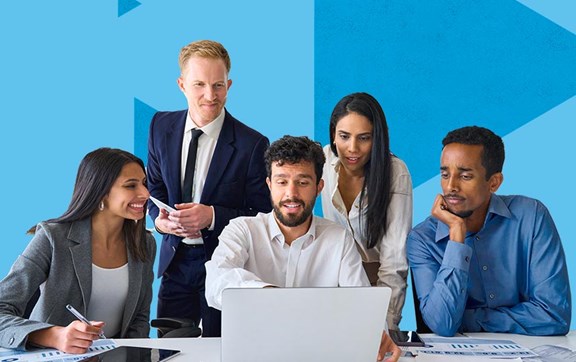 Gruppo di persone alla scrivania con tablet e pc che sorridono.